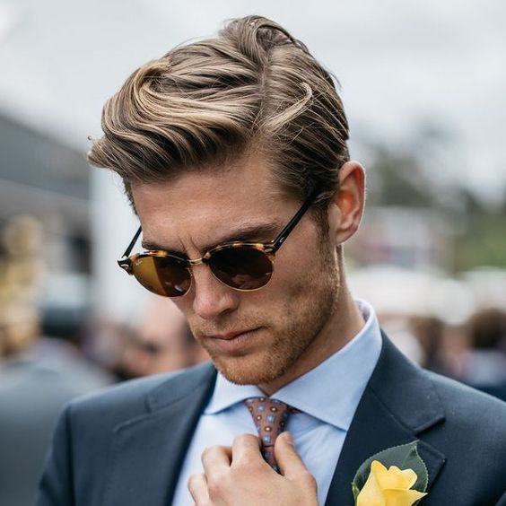 Man with the sunglasses and the side-parted look looking down 
